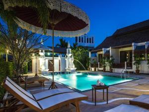 a swimming pool with chairs and an umbrella at Doltara Boutique Resort in Chiang Mai