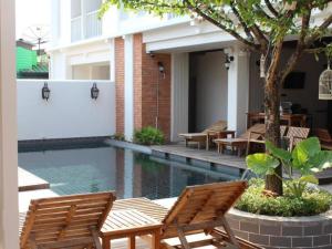 a swimming pool with wooden chairs next to a building at Baan Pimpisa in Bang Sare