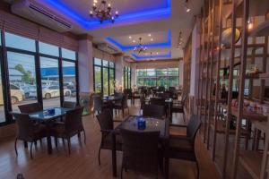 een restaurant met tafels, stoelen en ramen bij phatra boutique hotel in Udon Thani