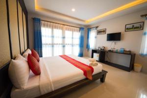 a bedroom with a large bed with a window at Poochommhok Resort in Sangkhla Buri