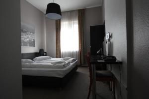 um quarto com uma cama, uma secretária e uma janela em Carlton Hotel em Frankfurt am Main