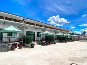 ein Gebäude mit grünen Sonnenschirmen auf einem Parkplatz in der Unterkunft Thongsuk Mini Resort in Pran Buri