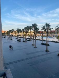 zwei Menschen gehen durch einen Park mit Palmen in der Unterkunft بورتو الجولف in El-Alamein + 1 Foto