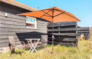 una sombrilla naranja sentada junto a una mesa y sillas en Huisje 4, en Grashoek