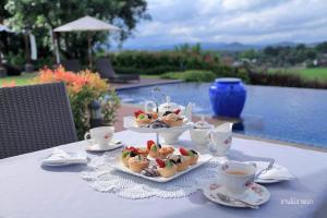 ein Tisch mit zwei Tellern mit Essen und Tassen darauf in der Unterkunft Nan Boutique Resort in Ban Hua Wiang Nua