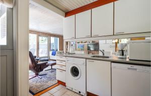 a kitchen with white cabinets and a washer and dryer at Holiday Home Høgevej Kolind Vi in Kolind