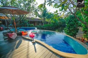 a swimming pool with an umbrella and a wooden deck at Panwana Resort in Rayong