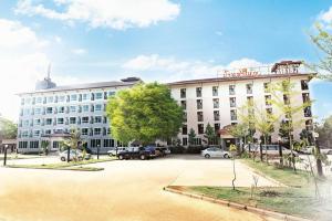 a large white building with cars parked in a parking lot at Baan Payai Resort in Ban Pang Kae