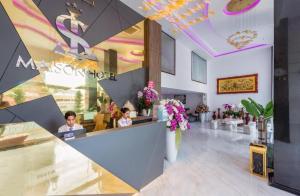 a lobby of a restaurant with two people sitting at a counter at Maison Hotel Phu Quoc in Phú Quốc