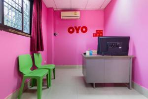 a pink room with two green chairs and a tv at OYO 577 For Love Hotel in Samut Sakhon +59 photos