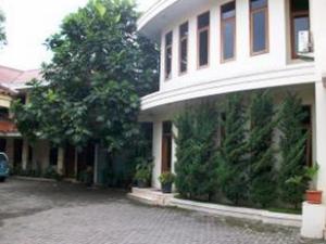 a white house with trees in front of it at Pilatus Hotel in Bandung