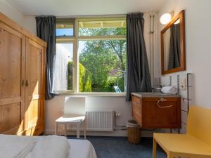 ein Schlafzimmer mit einem Bett, einem Fenster und einem Schreibtisch in der Unterkunft Bungalow near Dutch Beach with Garden in Oostkapelle