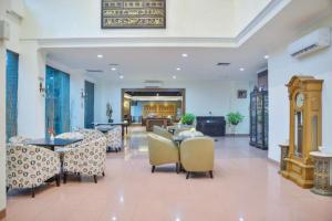 un vestíbulo con mesas y sillas y un reloj en Sleepzzz Hotel Senayan, en Yakarta