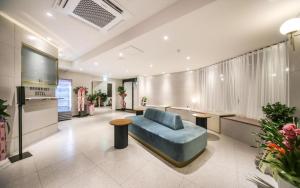 a living room with a blue couch and a tv at Changwon Brown dot Hotel Palyong in Changwon