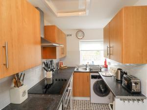 a kitchen with wooden cabinets and a dishwasher at Bedwine Cottage in Beadnell