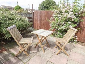 two chairs and a wooden table in a backyard at Bedwine Cottage in Beadnell +4 photos
