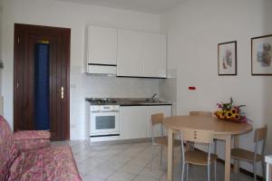 cocina con mesa y cocina con armarios blancos en Viviana, en Lignano Sabbiadoro