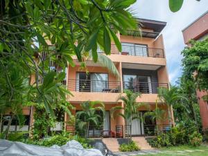 an orange building with trees in front of it at OYO 567 U Residence in Ban Lamai