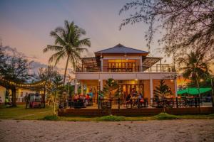 una casa con persone sedute ai tavoli di fronte ad essa di THE PP. BEACH RESORT THASALA a Nakhon Si Thammarat
