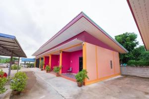 um prédio rosa e laranja com plantas em vasos em OYO 1044 Vassana ResortÃ¢â‚¬â€¹ em Sattahip