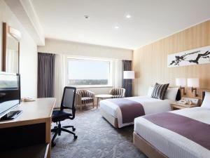 a hotel room with two beds and a desk at Hotel Nikko Narita in Narita