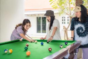 a group of three women playing a game of pool at Dudnapa Pool Villa Hua Hin in Hua Hin