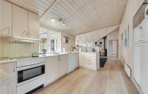 a large kitchen with white cabinets and a wooden floor at Holiday Home Bækholmen Ebeltoft I in Ebeltoft