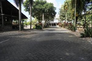 un camino de ladrillo con árboles y un edificio de fondo en OYO 93277 Villa Kemiloko Syariah, en Prigen