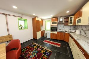 a kitchen with wooden cabinets and a red chair at Apartments Villa Begić in Sarajevo
