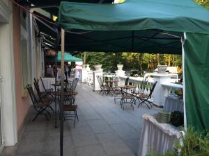 eine Terrasse mit Tischen und Stühlen unter einem grünen Sonnenschirm in der Unterkunft Hotel Colosseum in Olecko