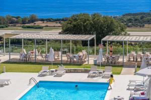 a pool with chairs and tables and a group of people at Drita Studios & Apartments in Svoronata