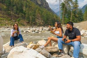カソルにあるThe Social Stays Kasol formerly ArtBuzzの川沿いの岩の上に座っている3人のグループ +42枚の写真