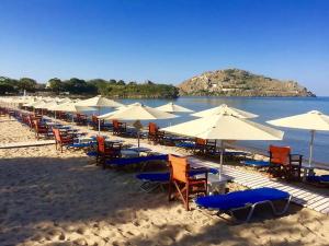 a row of chairs and umbrellas on a beach at Gea luxury apartment Myrina 1 in Myrina