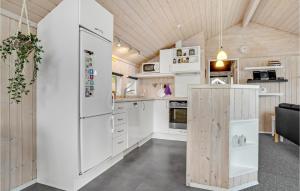 a kitchen with white cabinets and a large refrigerator at Holiday Home Bygmarken V in Sønder Bjert