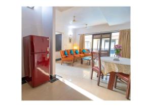 a living room and dining room with a red refrigerator at Lagoon Villa in Old Goa