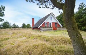 a red and white house in a field with a tree at Holiday Home Koubjerg J-934 in Toftum