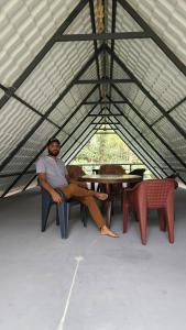 a man sitting in a chair in a tent at Vasu estate stay in Madikeri