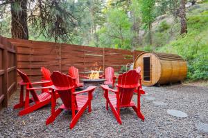 a group of red chairs and a table with a fire at White Pass Log Cabin Luxury Retreat in Rimrock