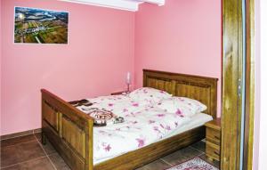 a bedroom with a bed with a pink wall at Awesome Home In Brzezno Szlacheckie in Brzeźno Szlacheckie +3 photos