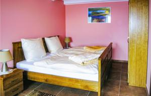 a bed in a room with a pink wall at Awesome Home In Brzezno Szlacheckie in Brzeźno Szlacheckie