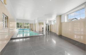 a swimming pool in a large room with a large window at Amazing Home In Væggerløse With Sauna in Marielyst +43 photos