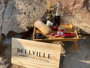 Una mesa con una botella de vino y un cartel. en Dellville Country House & Cottages, en Carnarvon