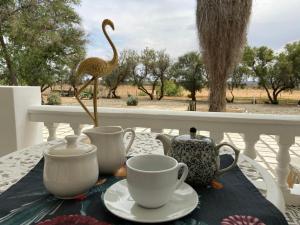 Una mesa con tazas de té y una estatua de pájaro sobre ella. en Dellville Country House & Cottages, en Carnarvon