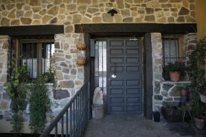 uma porta para uma casa de pedra com plantas no alpendre em Hostal Restaurante Alto Rey em Arroyo de las Fraguas