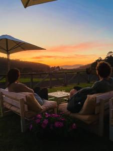 a group of people sitting on benches watching the sunset at Cabanas da Ría in Lires +108 photos