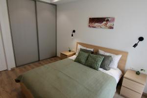 a bedroom with a large bed with a green blanket at Warmzy Home - Modern 2 Rooms Apartment With Free Parking in Vilnius