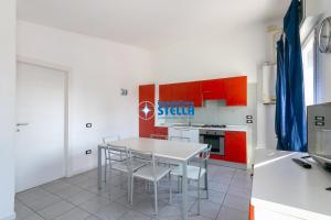 a kitchen with a white table and red cabinets at Condominio Milan in Lido di Jesolo