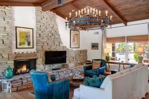 a living room with a fireplace and a chandelier at Casa de Mayo - Meredith Lodging in Palm Springs
