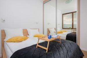グダニスクにあるGarnizon Apartment Hemara in Gdańsk Wrzeszcz by Noclegi Rentersのベッドルーム1室(黄色い枕とテーブル付きのベッド2台付) +10枚の写真