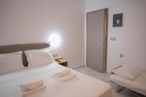 a white bedroom with a bed and a chair at Star Hotel in Rhodes Town